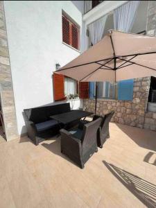 eine Terrasse mit 2 Stühlen und einem Sonnenschirm in der Unterkunft Apartments Fig&Olive in Zaton