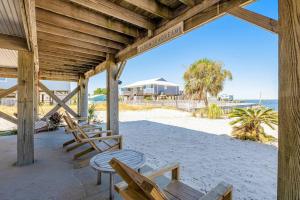 eine Veranda mit Stühlen und Tischen am Strand in der Unterkunft Bay Dreamin - Gulf Shores,Al in Gulf Shores