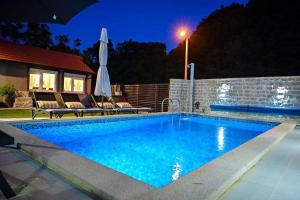 a swimming pool with an umbrella next to a house at Villa Sierra in Sinj