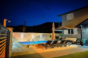 uma piscina com cadeiras e guarda-sóis ao lado de uma casa em Villa Sierra em Sinj
