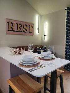 a white table with two glasses and plates on it at Wheelwright's Rest, Legbourne, Louth in Louth