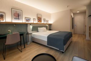ein Hotelzimmer mit Bett und Schreibtisch in der Unterkunft Hotel Münchwilen in Wil
