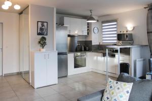 uma grande cozinha com armários brancos e um sofá em Bright well-appointed nest near Stade de France em Saint-Denis