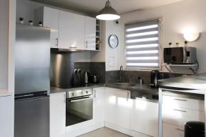 una cocina con armarios blancos y un reloj en la pared en Bright well-appointed nest near Stade de France, en Saint-Denis