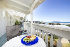 a plate of cheese and grapes on a table on a balcony at Mangawhai Lodge in Mangawhai