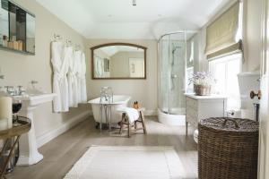 La salle de bains est pourvue d'une baignoire, d'un lavabo et d'une douche. dans l'établissement Gardeners Cottage, Wynyard Hall, 