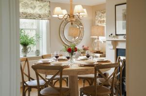 - une salle à manger avec une table, des chaises et un miroir dans l'établissement Gardeners Cottage, Wynyard Hall, 