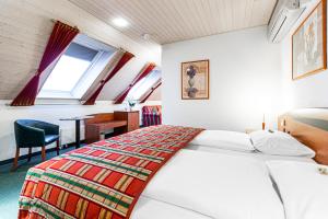 1 dormitorio con cama, escritorio y ventana en Hotel Münchwilen, en Wil