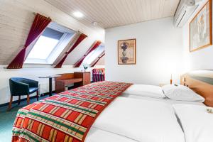 a bedroom with a bed and a desk and a window at Hotel Münchwilen in Wil