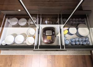 a refrigerator filled with white dishes and a cell phone at Kaika Inn in Osaka