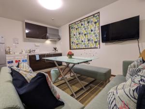 a living room with a table and a kitchen at Kaika Inn in Osaka