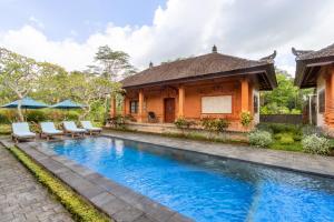 a villa with a swimming pool in front of a house at Bon Nyuh Bungalows in Gianyar
