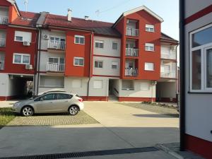 un'auto parcheggiata di fronte a un complesso residenziale di Apartman SUNSET a Sremska Mitrovica