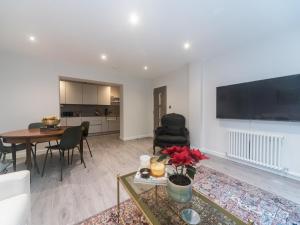 a living room with a table and a large flat screen tv at Pass the Keys Modern Apartment 2 Minute Walk From Station in Surbiton
