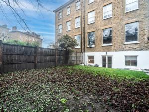 a yard in front of a building with a fence at Pass the Keys Modern Apartment 2 Minute Walk From Station in Surbiton