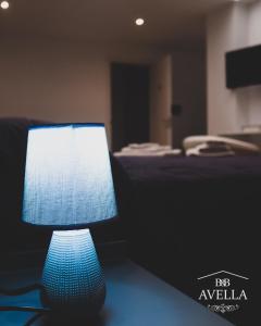 una lámpara azul sentada en una mesa junto a una cama en B&B Avella, en Chiubbica