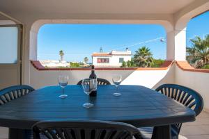 uma mesa azul com copos de vinho na varanda em House Calabernardo Sea Beach - Sicilia Vacanza em Calabernardo