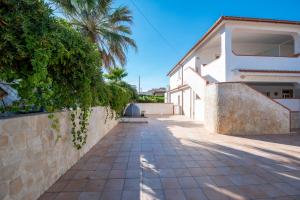 um caminho ao lado de uma casa com uma palmeira em House Calabernardo Sea Beach - Sicilia Vacanza em Calabernardo