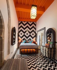 1 dormitorio con 2 camas y pared con espejo en Salut Maroc!, en Essaouira