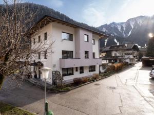 a large white building with mountains in the background at Appartement Partoll in Mayrhofen