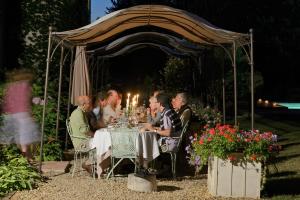 a group of people sitting at a table under a gazebo at Chateau Le Mas de Montet in Petit-Bersac