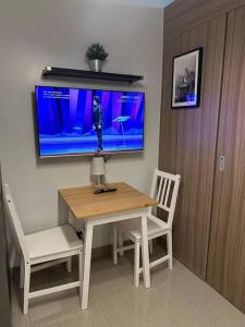 a room with a table and two chairs and a tv at Shore 2 Apartment with Balcony in Manila