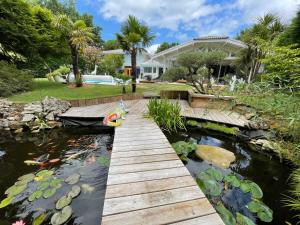 a wooden bridge over a koi pond in front of a house at La Maison Blanche de Lanton in Lanton