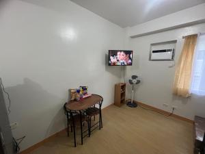 um quarto com uma mesa e uma televisão na parede em Suite in the City em Manila