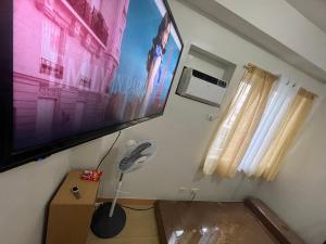 um quarto com uma televisão de ecrã plano e uma ventoinha em Suite in the City em Manila