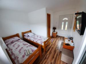 Habitación pequeña con 2 camas y TV. en Apartmani Biser Drine en Foča