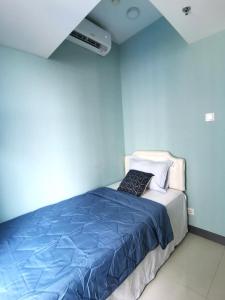 a bedroom with a bed with a blue wall at Benson Tower Surabaya Apartment 2BR by Le Ciel Hospitality in Lontar