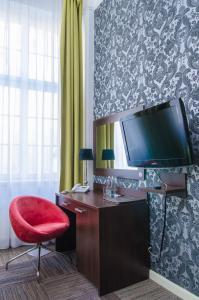 a room with a desk with a television and a red chair at Hotel Artus - Old Town in Gdańsk