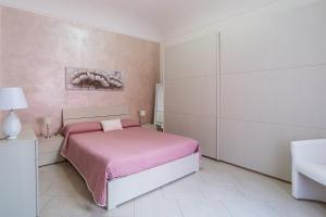 um quarto com uma cama rosa e um lavatório em Casa Maria em La Maddalena