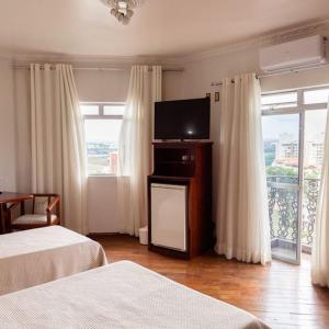 a hotel room with two beds and a flat screen tv at Castelar Novo Hotel in Varginha