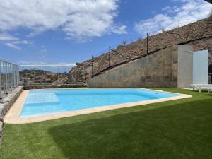 a large swimming pool in a yard with green grass at Villa Calm Ocean views by Infinity Summer in La Playa de Arguineguín