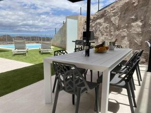 a white table and chairs on a patio with a pool at Villa Calm Ocean views by Infinity Summer in La Playa de Arguineguín