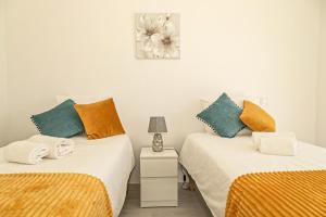 1 dormitorio con 2 camas y mesita de noche con lámpara en O PINHAL DO AVÔ, en Almancil
