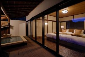 een slaapkamer met 2 bedden en een glazen wand bij Sakahijiri gyokushoen in Izu
