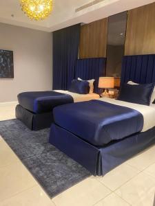 sypialnia z 2 łóżkami z niebieskimi kołdrami i żyrandolem w obiekcie Dana Hotel w mieście Burajda