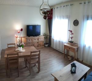 - un salon avec une table et une télévision dans l'établissement Entre Lacs et Volcans, à Aydat