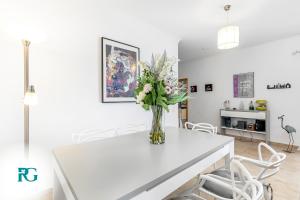 a white dining room with a vase of flowers on a white table at Luxury Penthouse Near City Center #1933 in Lagos +33 photos