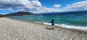 a young girl standing on a beach near the ocean at La Tiny House in Ushuaia