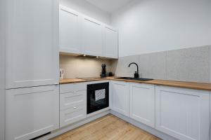 a white kitchen with white cabinets and a sink at Piotrkowska Street III by LookAp in Łódź