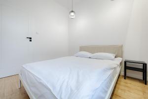 a white bed with white sheets and a side table at Piotrkowska Street III by LookAp in Łódź