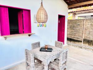 a dining room with a table and chairs and pink windows at Gostoso Familly Chalés - Beira Mar in São Miguel do Gostoso