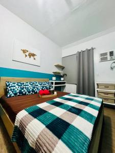 ein Schlafzimmer mit einem Bett mit einer karierten Decke in der Unterkunft Cozy Place Anuva Residences in Manila