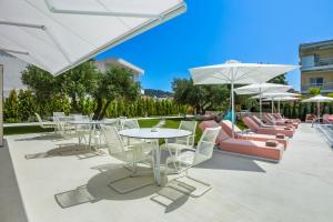 a patio with white tables and chairs and umbrellas at Cocoοns Suites & Villas Fourka in Fourka