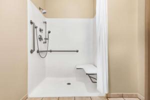 a white bathroom with a shower with a bench at Super 8 by Wyndham Savannah in Savannah