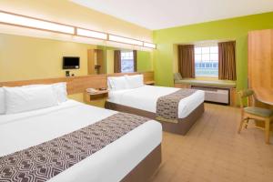 um quarto de hotel com duas camas e uma cadeira em Microtel Inn & Suites by Wyndham Delphos em Delphos