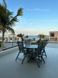 einen Tisch und Stühle auf einer Terrasse mit Meerblick in der Unterkunft The Beach House in Muscat